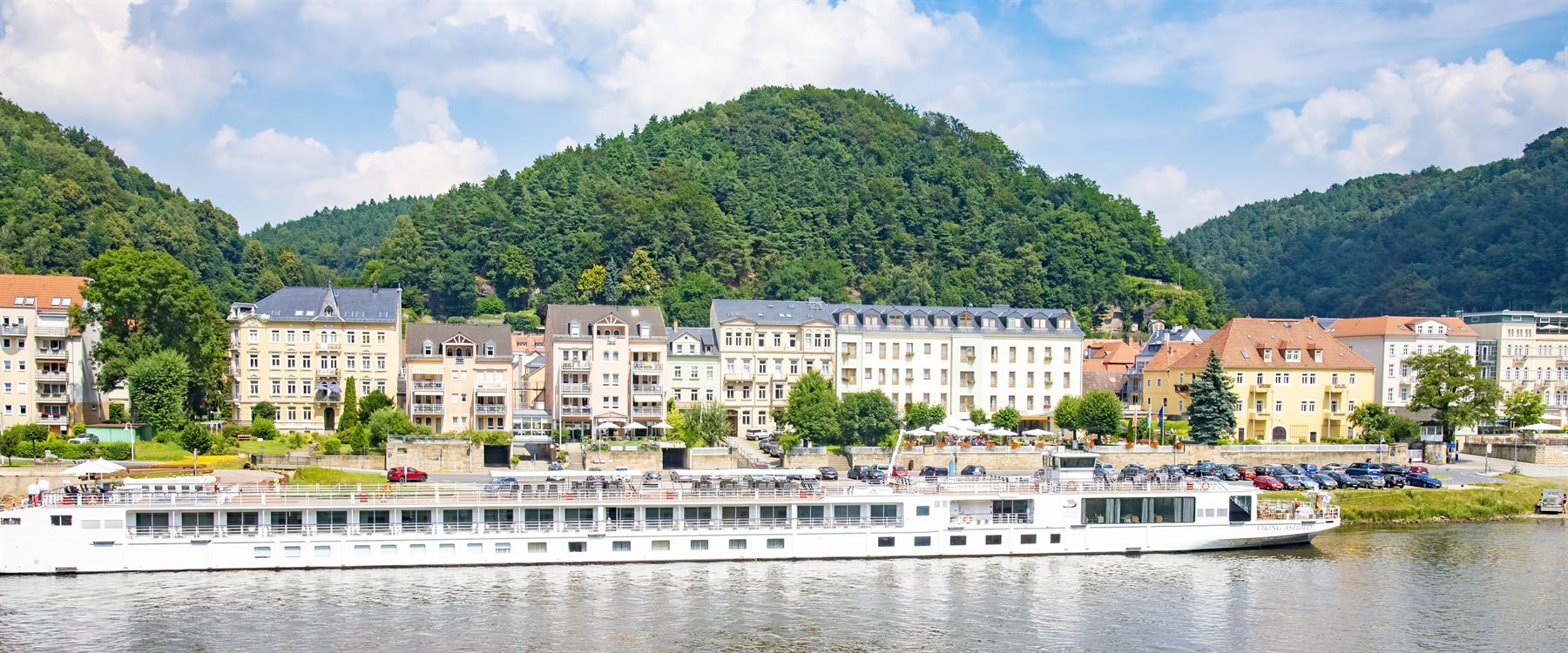 River cruise ship moored in front of a hillside town